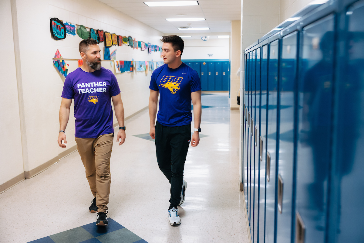 Alumni mentor teacher and student teacher walking hallway by lockers