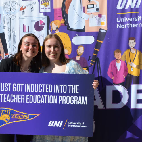 Two students in front of banner at convocation 